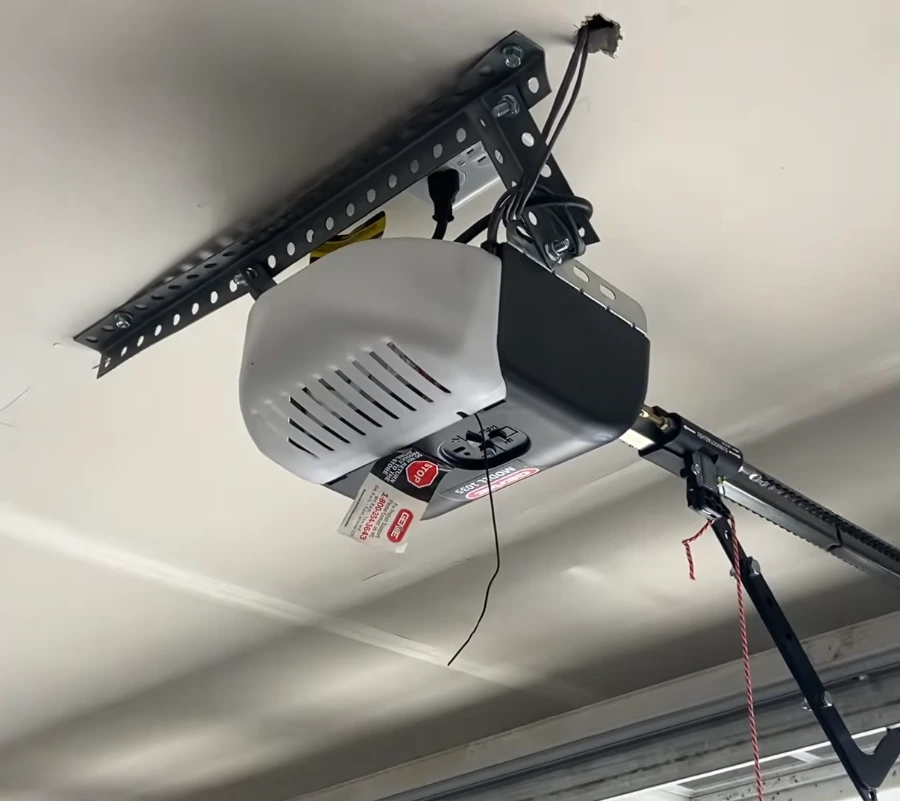 Close view of a Genie chain drive garage door opener motor unit and mounting bracket on a garage ceiling