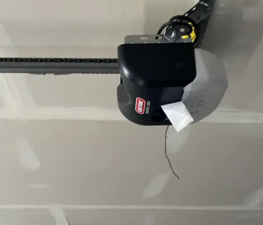 Ceiling-mounted Genie Model 1035 chain drive garage door opener with drive rail in a Lubbock garage