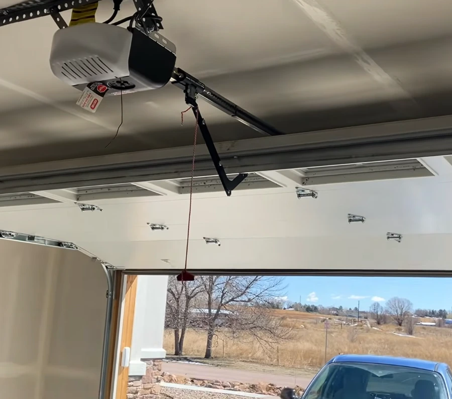 Garage door opener and rail above a partly open door looking out onto West Texas grassland near Lubbock
