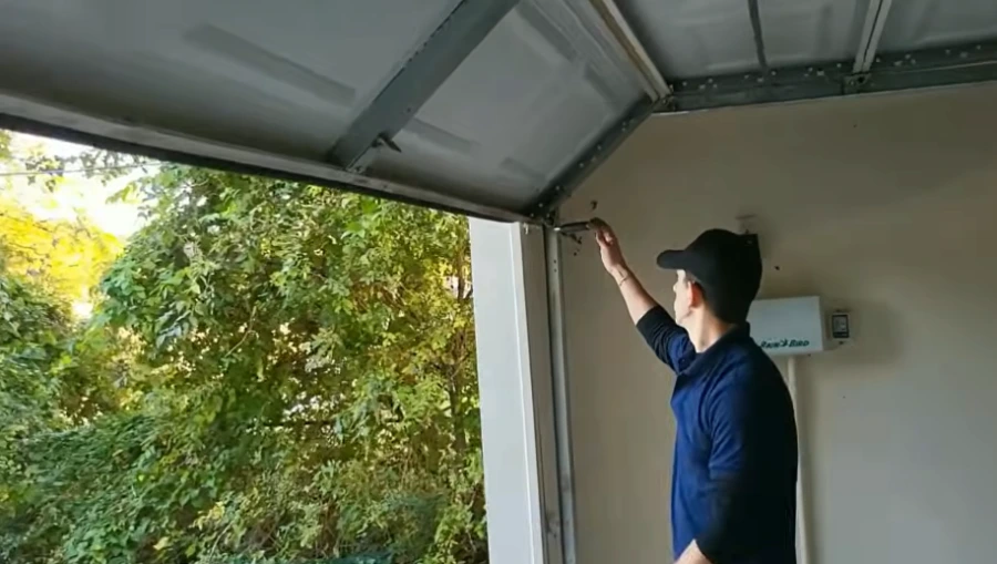 Garage door technician inspecting the top section and track of a residential garage door in Lubbock, TX