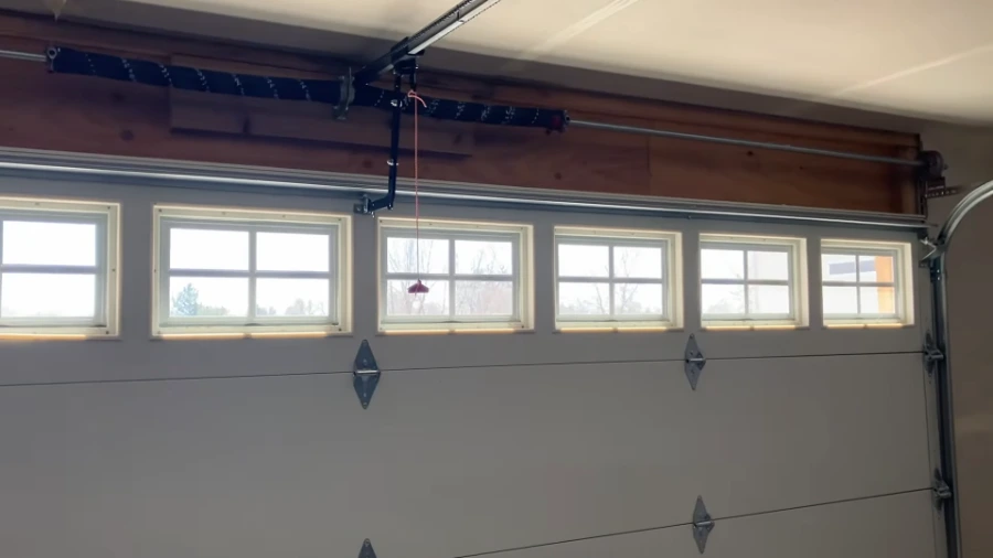 Wide sectional garage door with a row of windows and the torsion bar and spring assembly mounted above